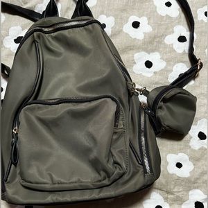A small green backpack with multiple pockets and a coin pouch attached.